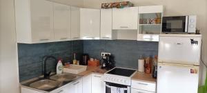 a kitchen with white cabinets and a sink and a refrigerator at Múzsa Apartman in Siófok +17 photos