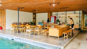 a woman standing in a kitchen with tables and chairs at Vả Riverside Retreat in Hue