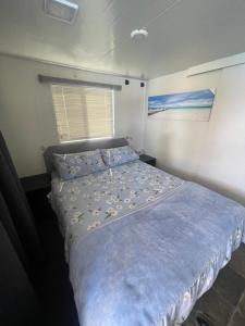 a bedroom with a bed with blue sheets and a window at Mandurah Houseboat Just Chillin in Mandurah