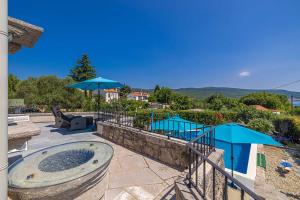 a hot tub on a patio with umbrellas at Rustikalna kuća za odmor VILLA MARE in Kornić