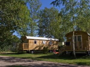 a wooden trailer and a house in the grass at camping les pêcheurs in Pont-de-Poitte