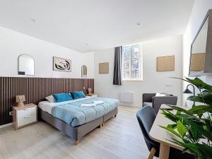 a bedroom with a bed and a table and a couch at Tour d'Auvergne - Appartements en plein centre ville, proche de la cathédrale et de la place de Jaude in Clermont-Ferrand