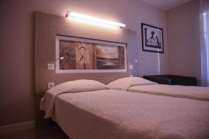 a hotel room with two beds and a picture on the wall at Résidence Château du Mée in Le Mée-sur-Seine