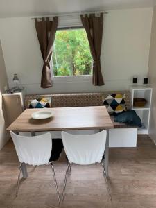 a dining room table with two white chairs and a window at Løgballe Camping & Cottages in Stouby