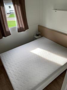 a white bed in a room with a window at Løgballe Camping & Cottages in Stouby