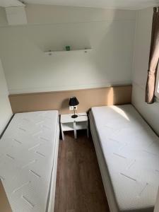 a room with two beds and a table with a lamp at Løgballe Camping & Cottages in Stouby