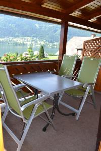 a table and chairs on a balcony with a view of the water at Merlschober, Ferienwohnung 3, Ossiacher See in Ossiach