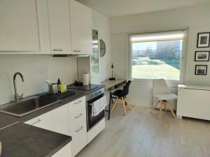 a kitchen with white cabinets and a sink and a window at Cozy Apartment in Nørresundby
