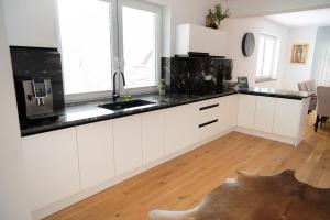 a kitchen with white cabinets and black counter tops at Penzión Slnečná in Lendak