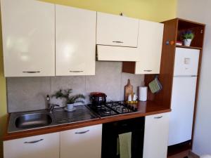 a kitchen with white cabinets and a sink and a stove at Casa vacanze sa minda noa whit a private garden in Olbia