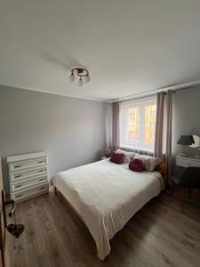 a bedroom with a large white bed and a window at Apart Konopnicka in Augustów