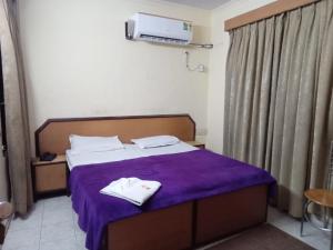 a bedroom with a bed with purple sheets and towels on it at hotel shree krishna vaishnav in Agra