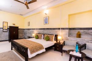 a bedroom with a bed and a couch and a chair at Kalyan Villa Heritage Stay in Udaipur