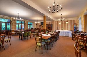 a restaurant with tables and chairs and a chandelier at Hotel Stara Posta in Filipovice