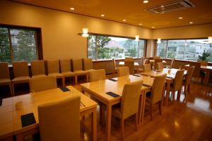 un restaurante con mesas y sillas de madera y ventanas en Shiki Resort Prego Hayama, en Hayama