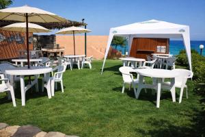 a group of tables and chairs under an umbrella at Hotiday Castelsardo Spiaggia in Castelsardo