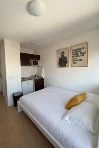 a bedroom with a white bed with a yellow pillow on it at Apparteo Strasbourg in Strasbourg
