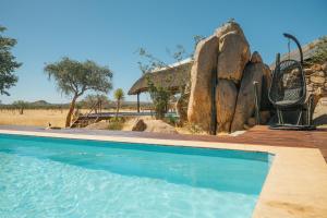 a swimming pool in front of a house with a rock wall at Ohorongo Tented Camp in Kaneb Pos +21 photos