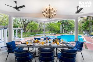 a dining room with a table and chairs and a pool at StayVista at Ananta - Breakfast Included & Basketball Court in Bangalore +24 photos