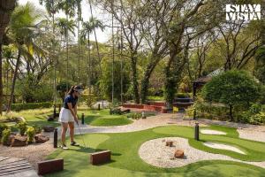 a woman playing golf on a miniature golf course at StayVista at Ananta - Breakfast Included & Basketball Court in Bangalore