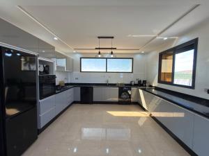 a large kitchen with black and white counters and windows at Villa Bonheur - Piscine sans vis-à-vis in Berkane