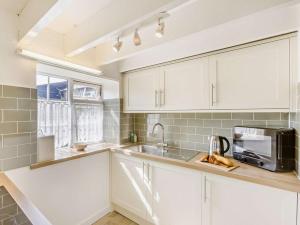 a kitchen with white cabinets and a sink and a microwave at 2 Bed in Bideford oc-60428 in Westward Ho