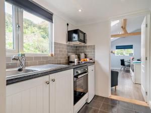 a kitchen with white cabinets and a sink and a window at 1 Bed in Bridport oc-94617 in Chideock +10 photos