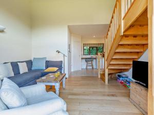 a living room with a blue couch and a staircase at 1 Bed in Tiverton oc-94766 in Bampton