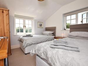 two beds in a bedroom with white walls and windows at 2 Bed in Crediton oc-51275 in Stockleigh Pomeroy