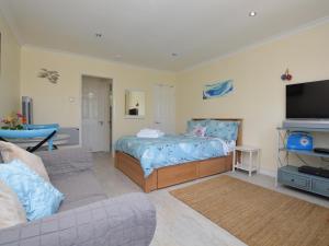 a bedroom with a bed and a couch and a tv at 1 Bed in Bridport oc-41890 in Charmouth