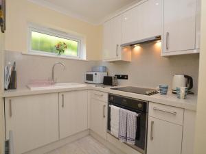 a kitchen with white cabinets and a sink at 1 Bed in Bridport oc-41890 in Charmouth
