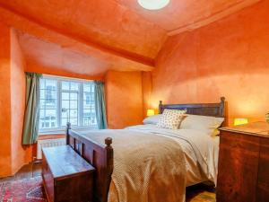 a bedroom with orange walls and a bed and a window at 4 Bed in Minehead oc-90504 in Dunster