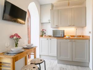 a kitchen with white cabinets and a wooden table at 1 Bed in Okehampton oc-78799 in Hatherleigh +15 photos