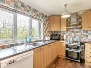 a kitchen with wooden cabinets and a sink and two windows at 2 Bed in Taunton oc-41906 in Cothelstone +14 photos