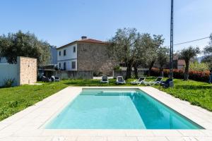 a swimming pool in a yard with two chairs and a house at Casa Eido Doce by House and People in Barcelos