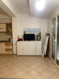 a kitchen with white cabinets and a tv on the wall at Arbaría vacation home in Cava D'aliga
