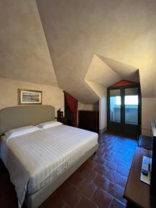 a bedroom with a bed and a desk and window at Tenuta Baràc in Alba