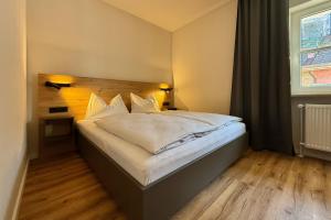a bedroom with a white bed with a wooden headboard at feinzeit am Windfelder See - Ruhe & Natur nahe Bamberg in Stegaurach