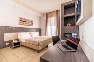 a hotel room with a bed and a desk with a laptop at Napoli Suite in Naples