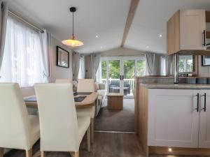 a kitchen and living room with a table and chairs at Eth Melyn Caravan Holiday in Grampound
