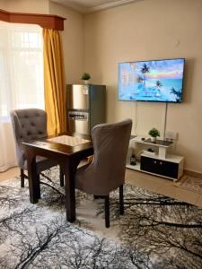 a living room with a table and a tv at Rose homes in Mombasa +1 photo