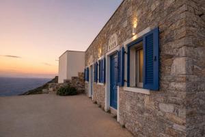 a stone building with blue windows and the ocean at Dreamy View in Folegandros in Áno Meriá