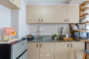 a kitchen with wooden cabinets and a black and white refrigerator at Condo in Cubao, Sunset & City Lights Chasing in Manila