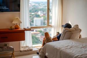 a woman sitting in a chair looking out a window at Condo in Cubao, Sunset & City Lights Chasing in Manila