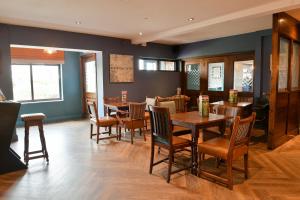 a dining room with wooden tables and chairs at The Broughton Hotel by Greene King Inns in Milton Keynes