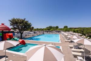 a swimming pool with umbrellas and a water slide at Club del Sole Adriatico Cervia Easy Camping Village in Cervia