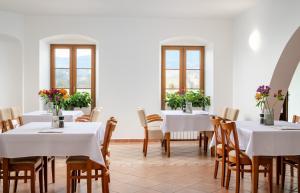 a dining room with white tables and chairs and windows at Hotel Pohoda in Staré Město