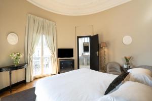 ein Schlafzimmer mit einem weißen Bett und einem Fernseher in der Unterkunft Le Cavendish in Cannes
