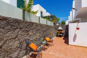 a patio with two chairs and a table and a stone wall at Villa Sunshine Lanzarote by Villa Plus in Teguise