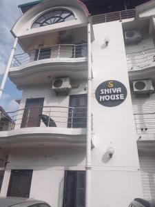 a white building with a sign on the side of it at Shiva House in Dehradun